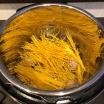 Gebroken pasta toevoegen om Instant Pot Spaghetti met gehaktballen klaar te maken. Gepresenteerd door Instant Pot Lekker!